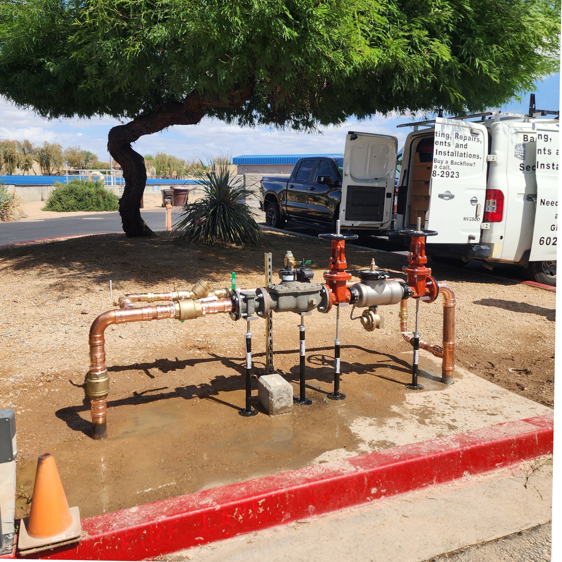 Completed outdoor backflow repair with copper piping and service vehicle nearby